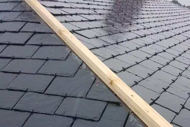 Leien tijdens het dekken — Een deel van een leien dakvlak met zichtbaar latwerk aan de rand.