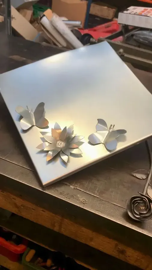 Metalen details op de werkbank — Gevormde metalen bloemen en kleine ornamenten naast het plaatmateriaal.